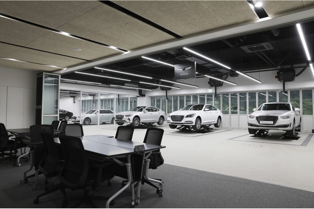 Showroom interior with white sedans on lifts and meeting tables
