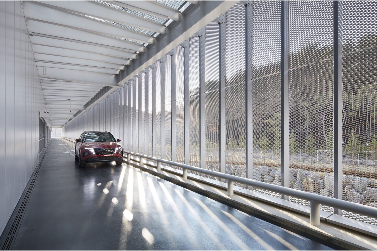 Red SUV in a light-filled mesh-walled corridor