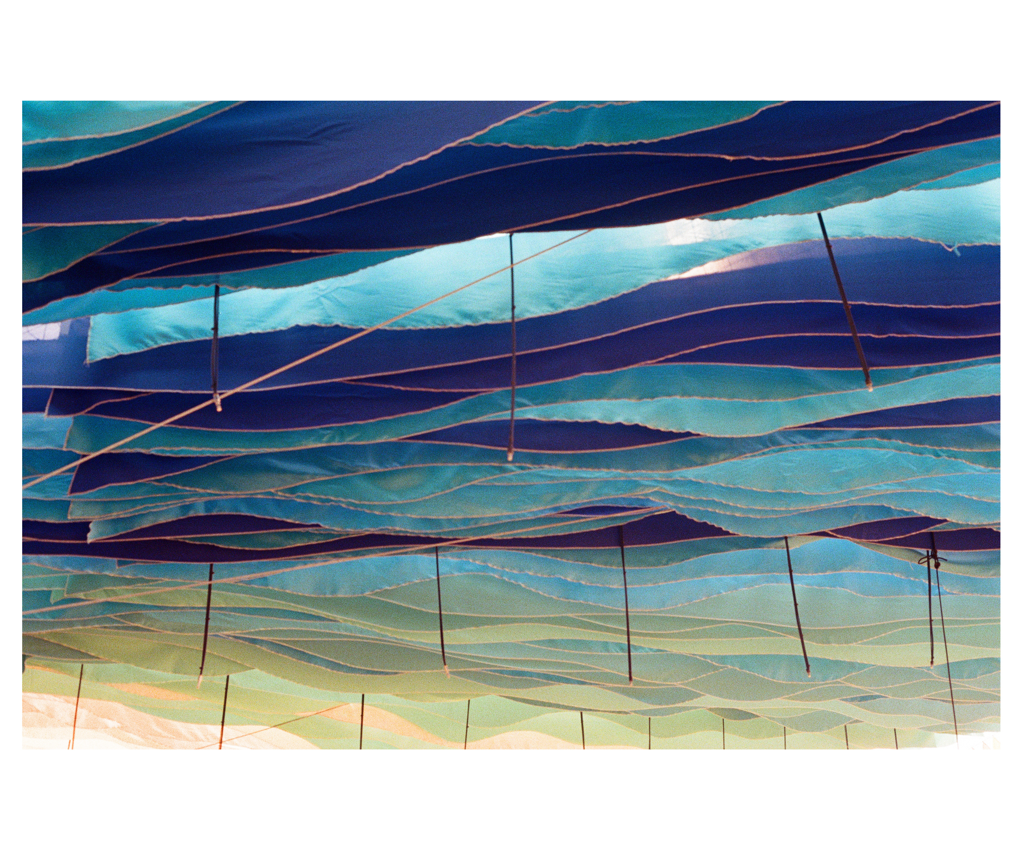 Looking up at layered blue and teal fabric strips