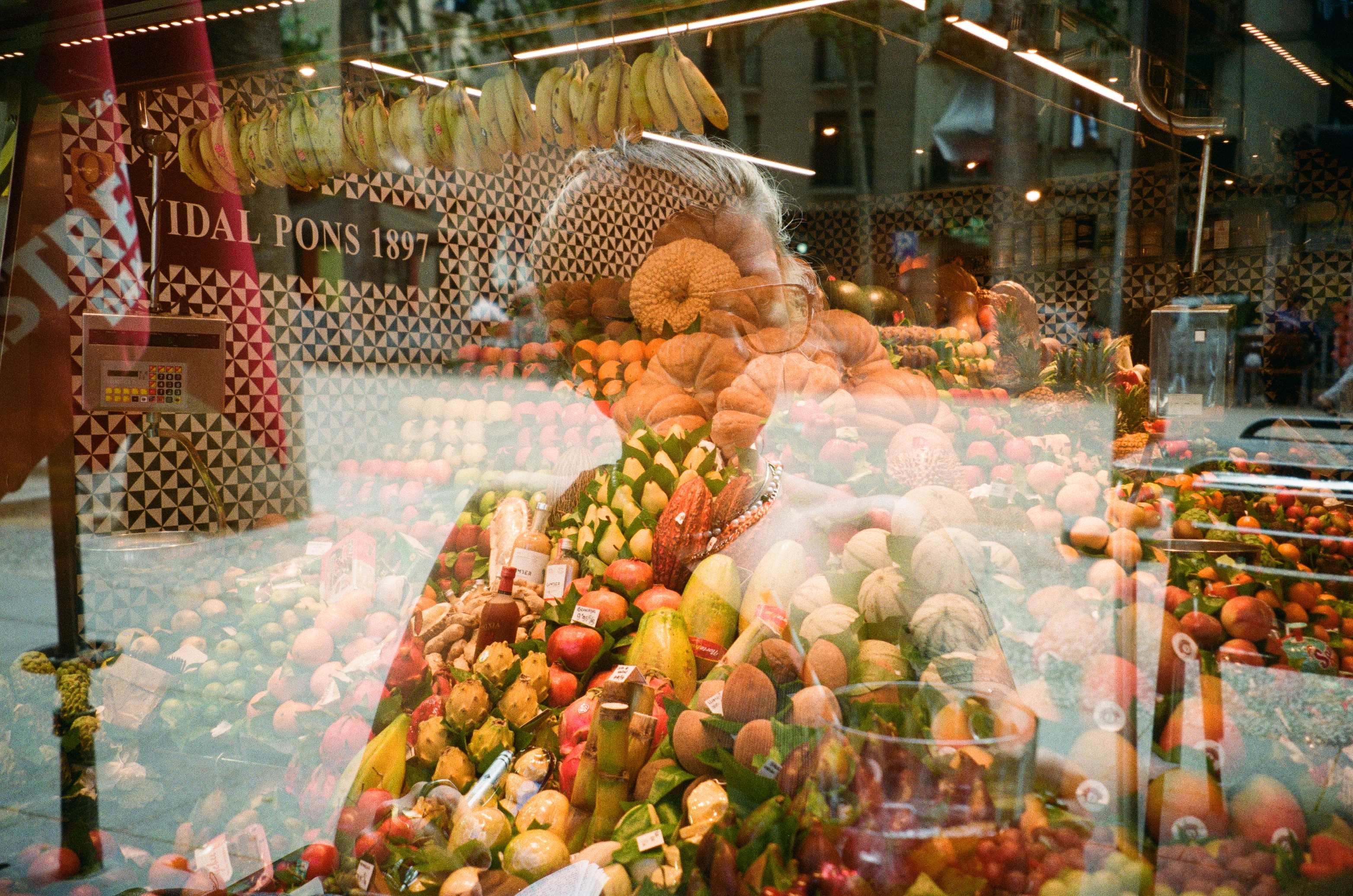 Double exposure of a woman's silhouette over a fruit stall window
