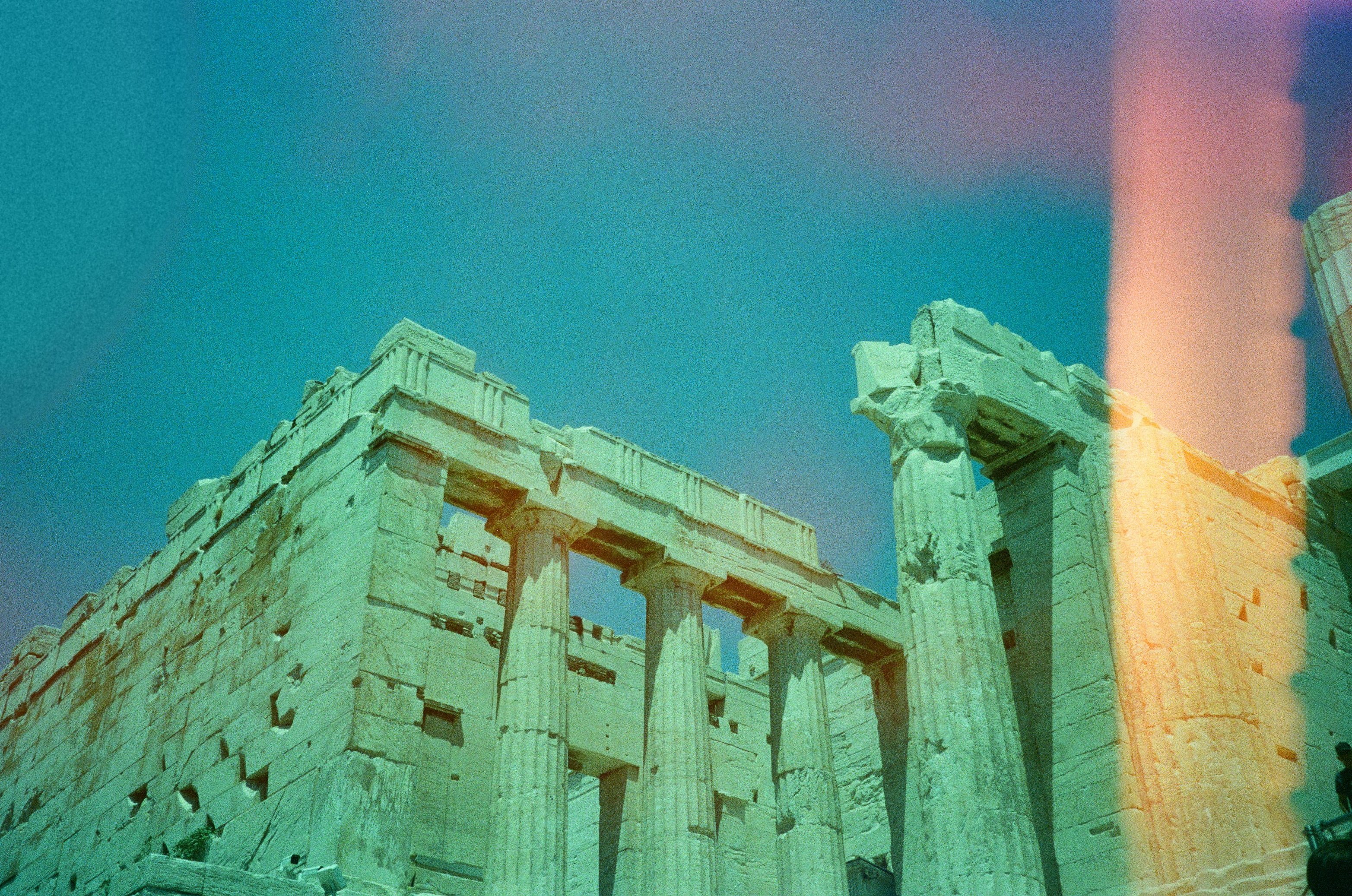 Doric columns of a ruin under a teal sky with light leaks