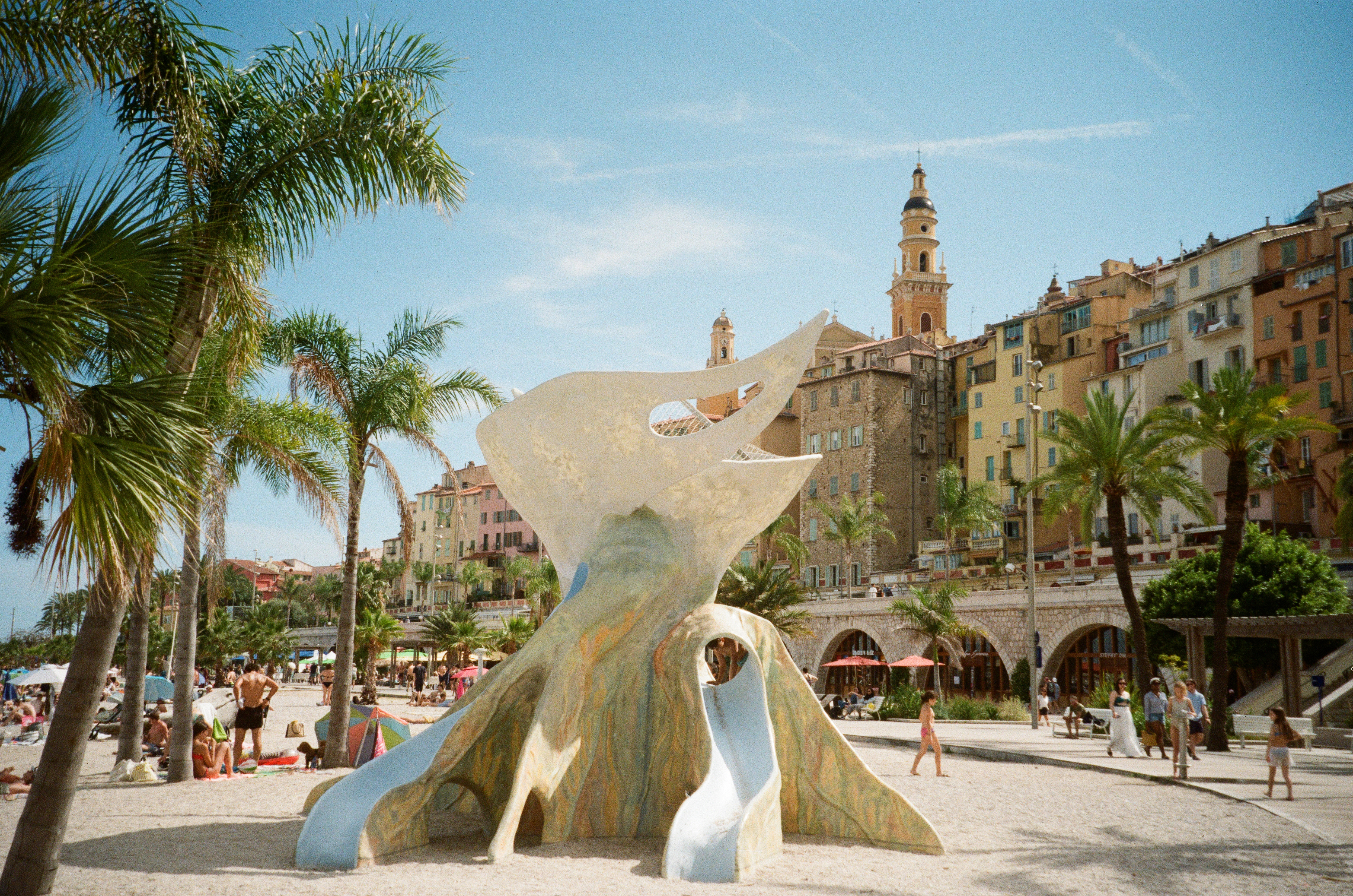 Sculptural beach playground below a hillside town