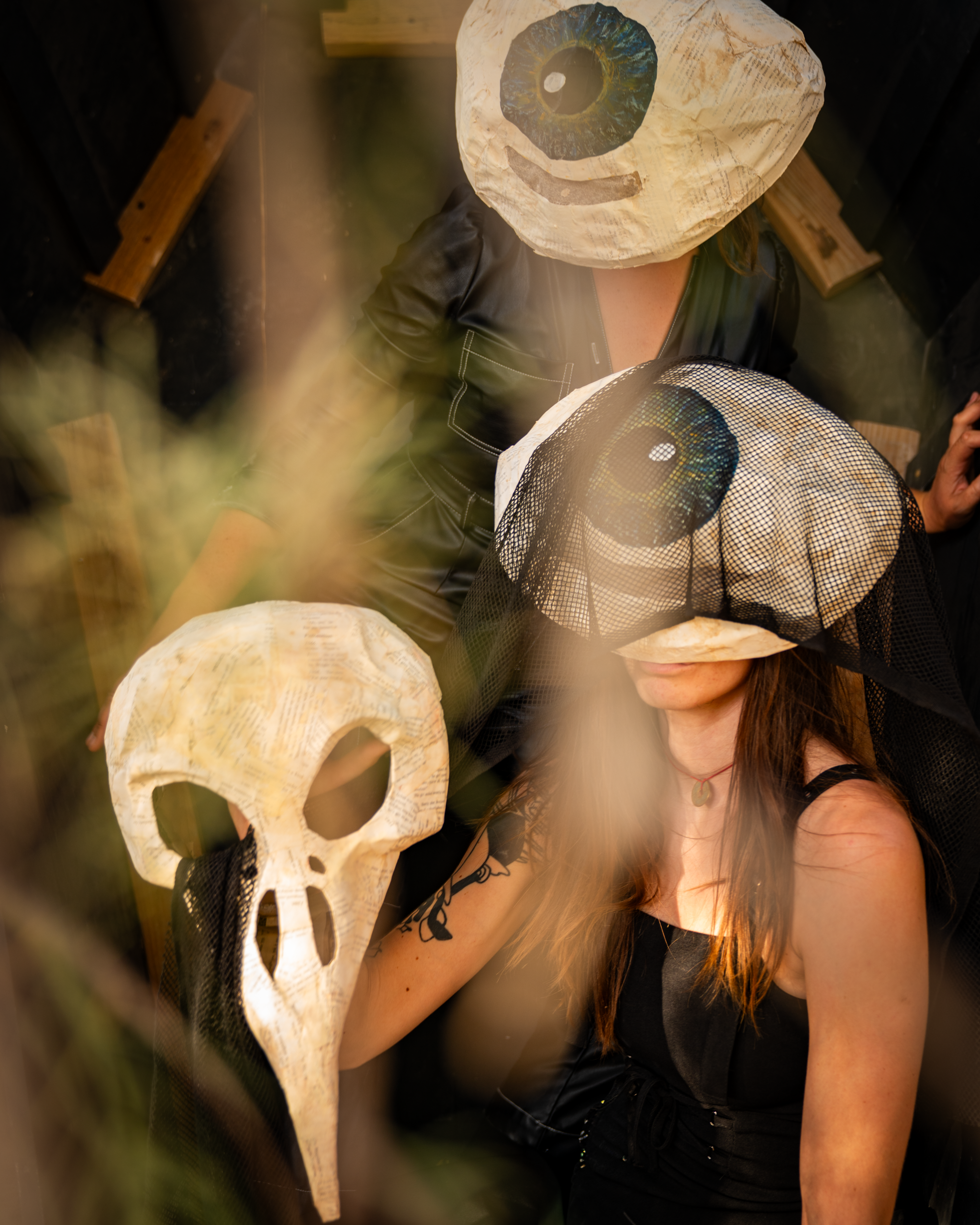 Close-up of two eye hats and a bird-skull mask inside the coffin, framed by blurred branches